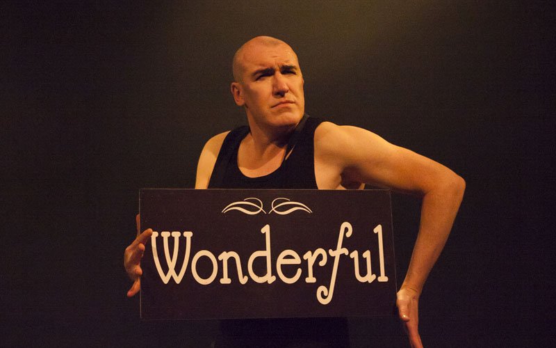 Actor Pat Kinevane holds a sign with 'Wonderful' written on it, in a scene from his play 'Silent.