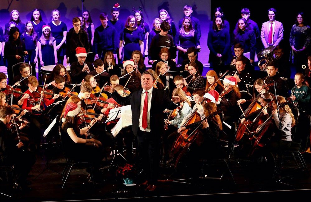 Conductor Vincent Kennedy stands in front of the Donegal Youth Orchestra and guests on stage at An Grianán.